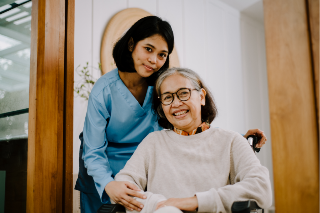 A young woman hugs an older woman who is sitting in a wheelchair