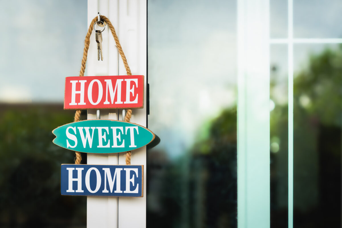 A sign reading "Home Sweet Home" hangs from a door along with some house keys