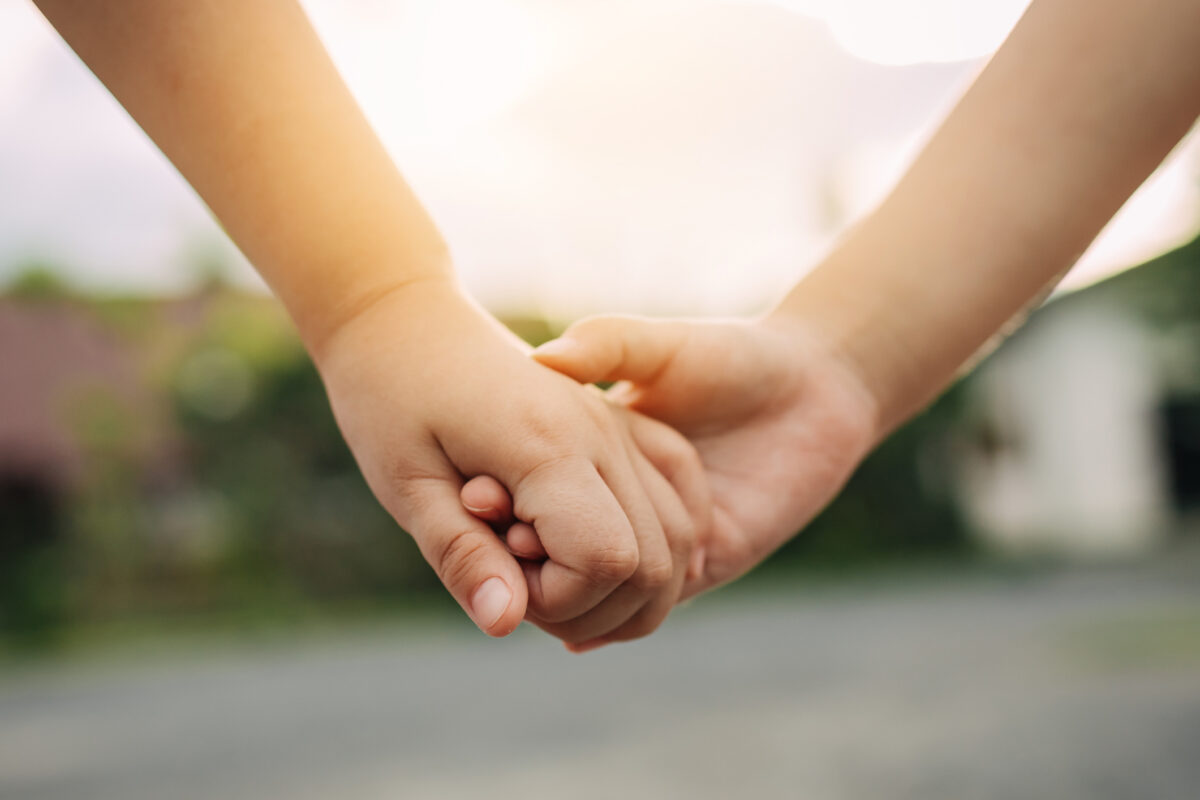 A close-up of two children holding hands