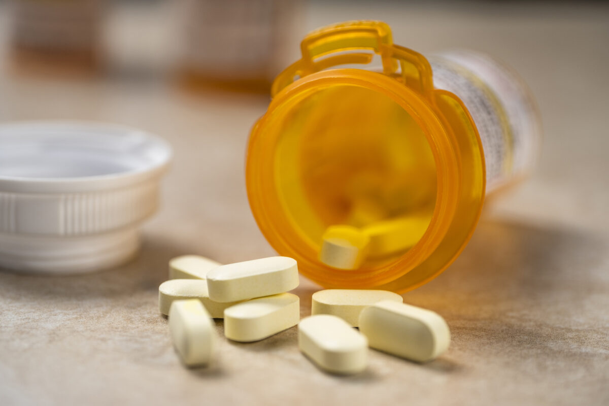 A bottle of prescription pills spilling out onto a counter