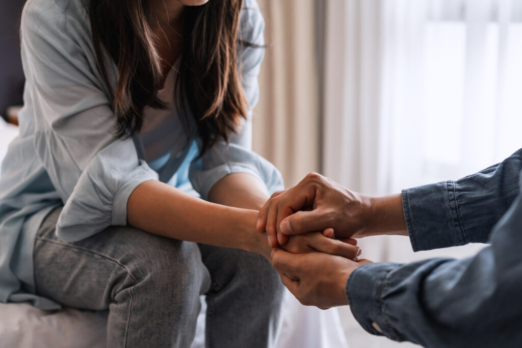 Close up of someone holding a woman's hands to provide comfort
