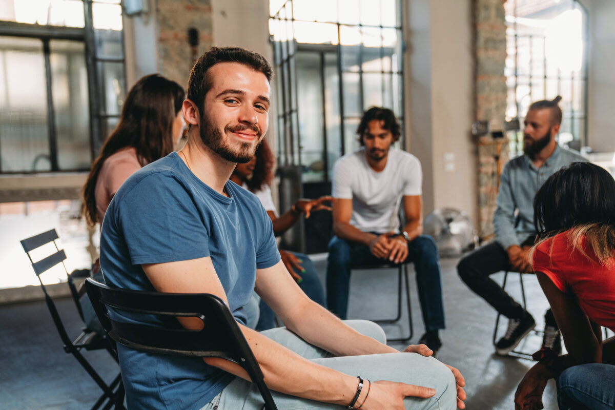 A man looks at the camera during a group therapy session