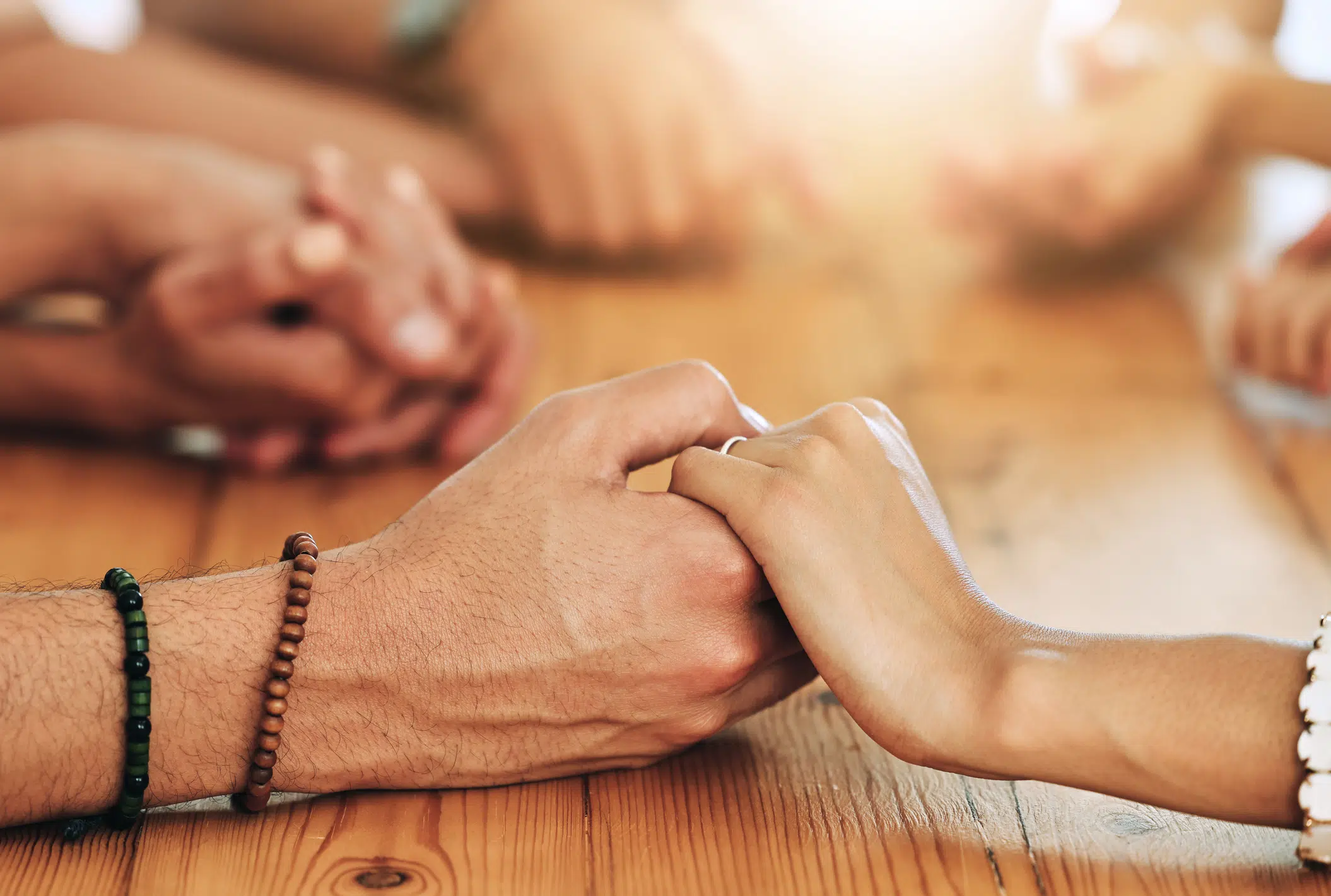 Close up of a group of people holding hands across a table