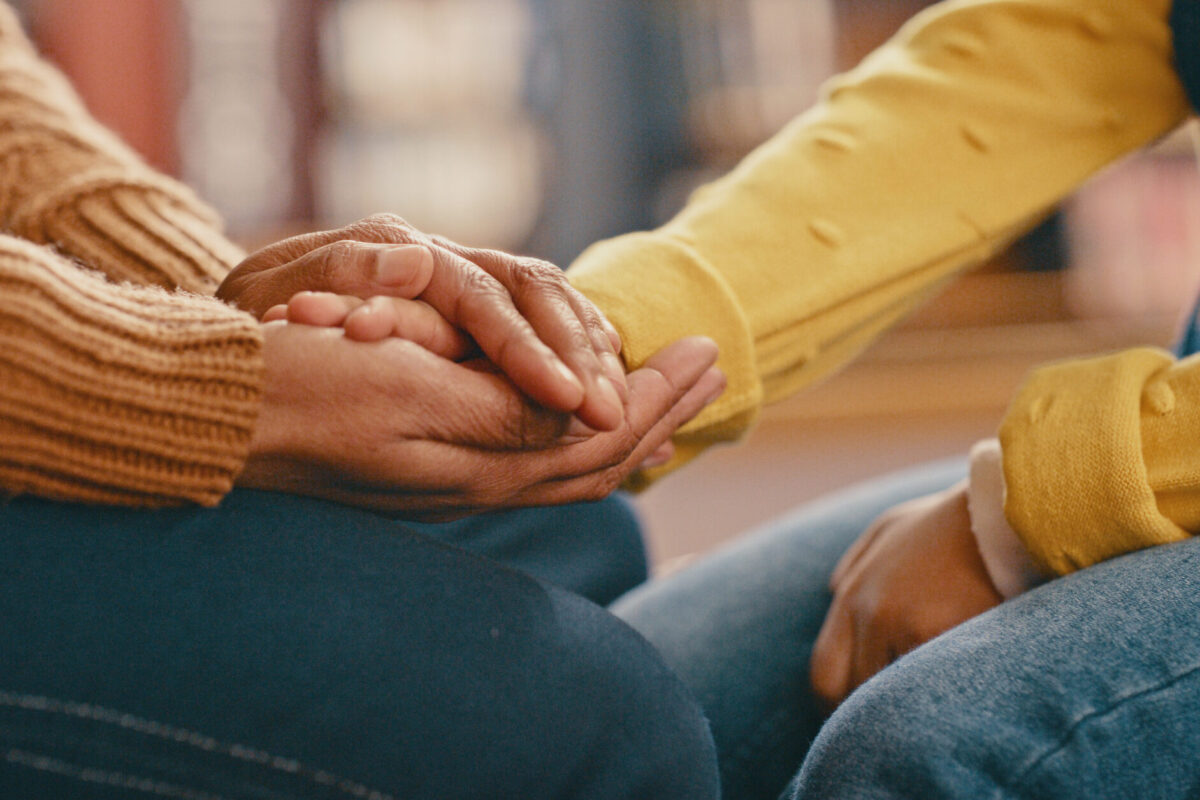 Close-up of two people holding hands in support