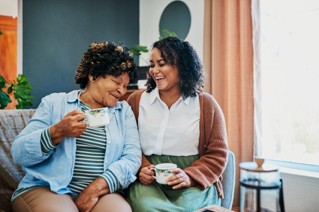 A mother and daughter laugh as share some tea